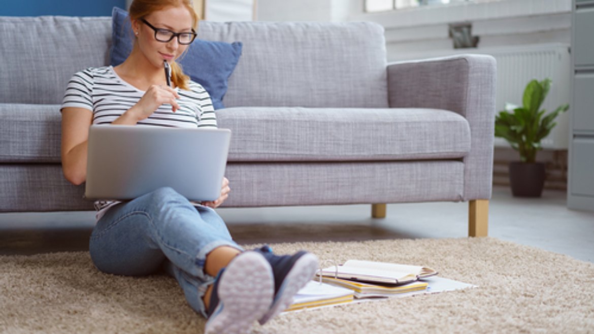 Young woman studying from home with her laptop and course books